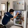Refrigerator repair technician repairing a refrigerator at customer home.
