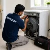 Washing machine repair technician servicing a washing machine at customer home.